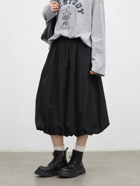 Model wearing a gray graphic sweatshirt with a black midi skirt and black lace-up boots