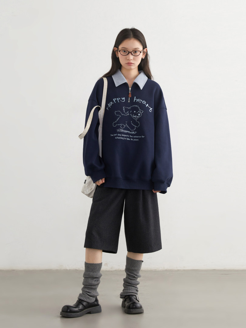 Model wearing a navy oversized sweatshirt with a collared neckline and printed graphic, styled with shorts and leg warmers