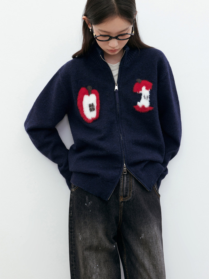 Model wearing a navy zip-up fuzzy cardigan with red and white graphic patches