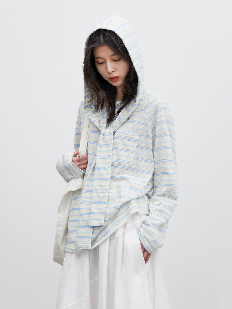 Model wearing a light striped hooded top with a white skirt