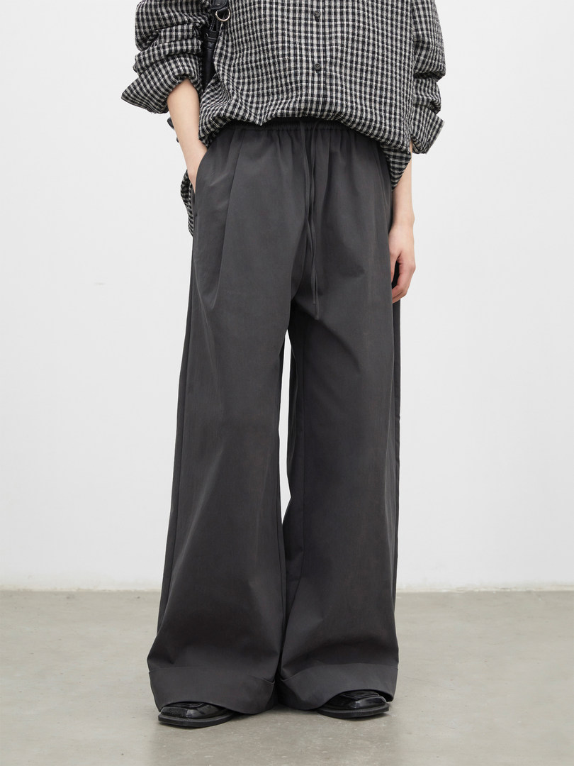 Model wearing dark wide-leg pants with a black-and-white checkered shirt