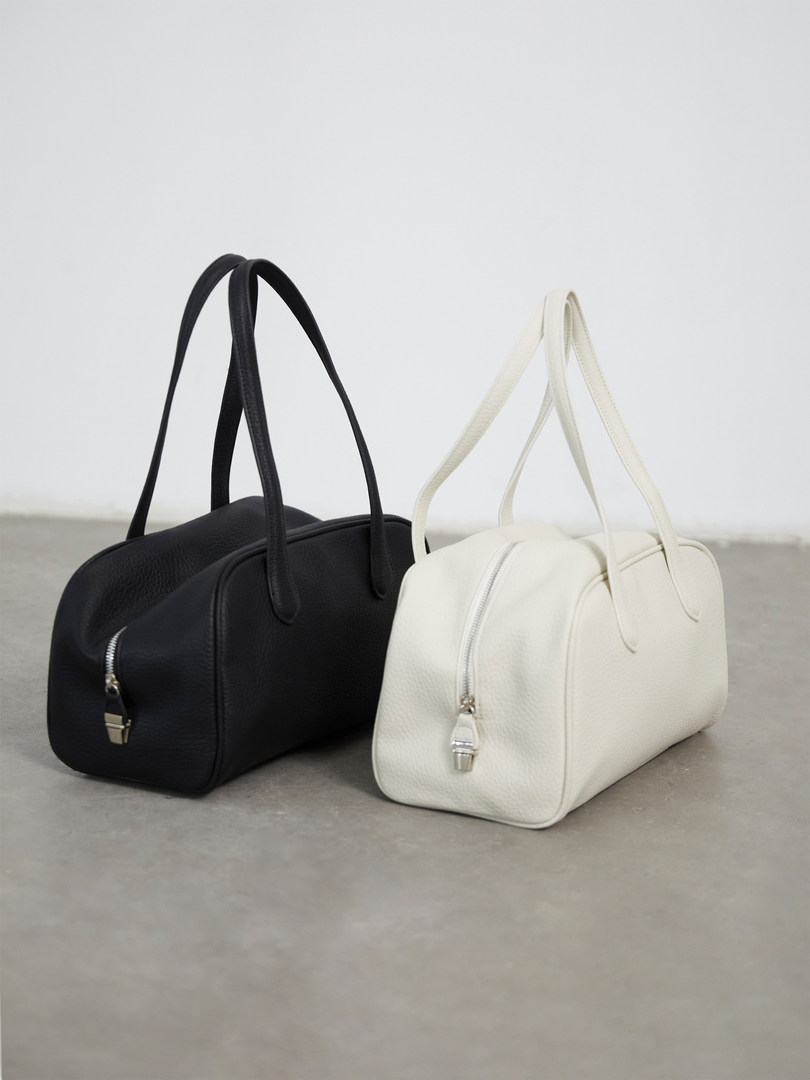 Two structured handbags, one black and one white, displayed on a plain background
