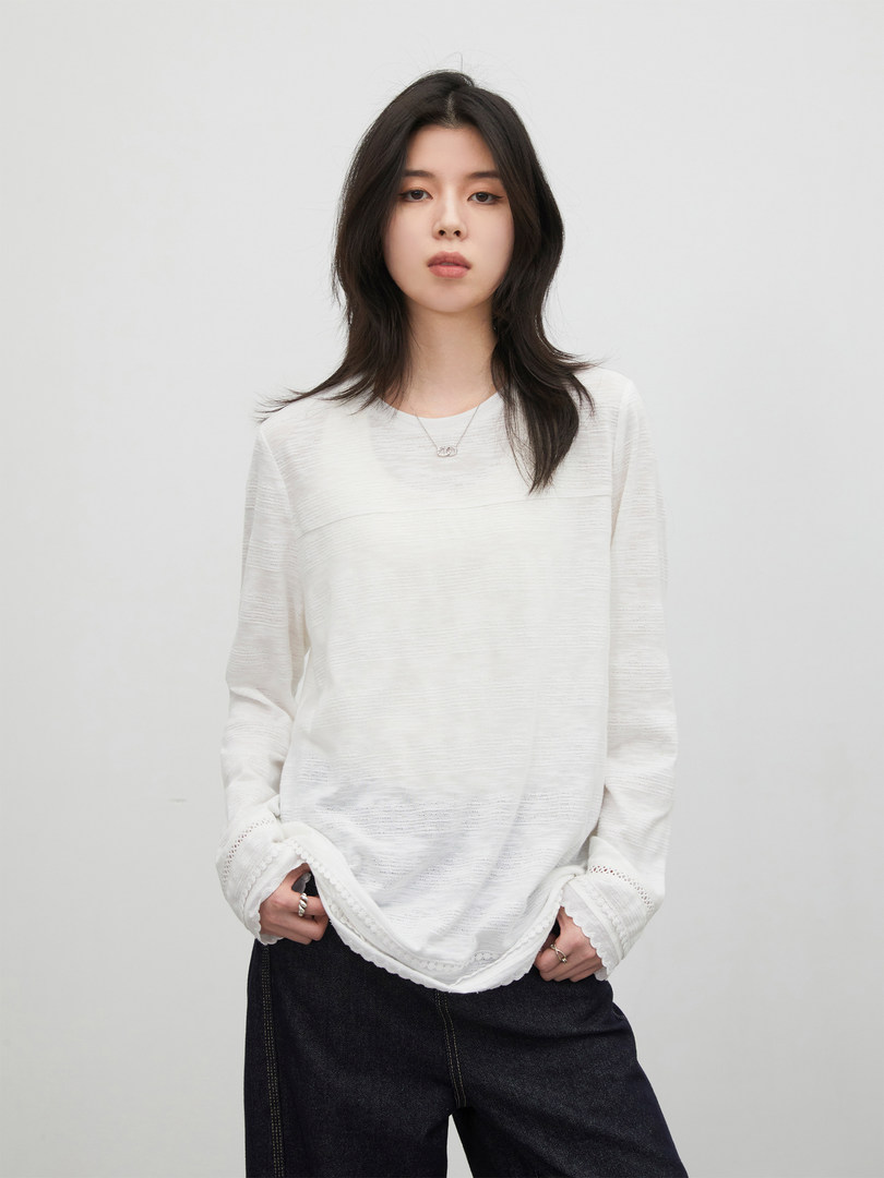 Model wearing a white long-sleeve blouse with a loose fit