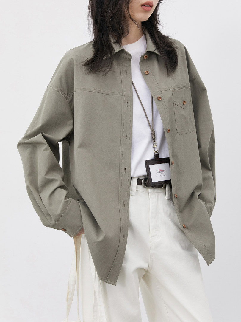 Model wearing an olive-green button-up overshirt jacket with a white top and cream pants