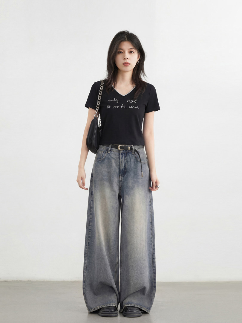 Model wearing a black graphic T-shirt with wide-leg faded jeans