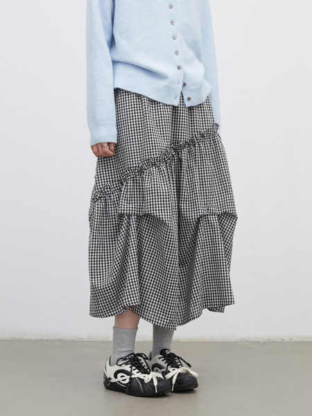 Model wearing a black-and-white gingham ruffled skirt with a light blue cardigan
