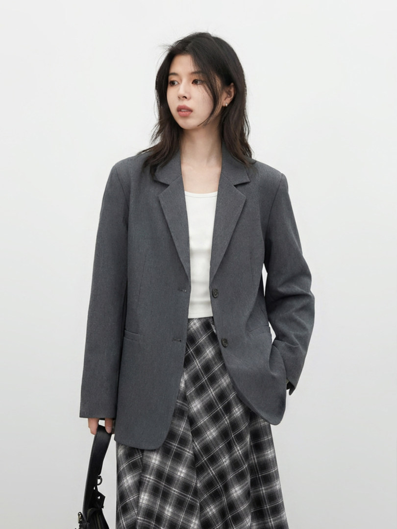 Woman wearing a gray blazer with a plaid skirt and white top
