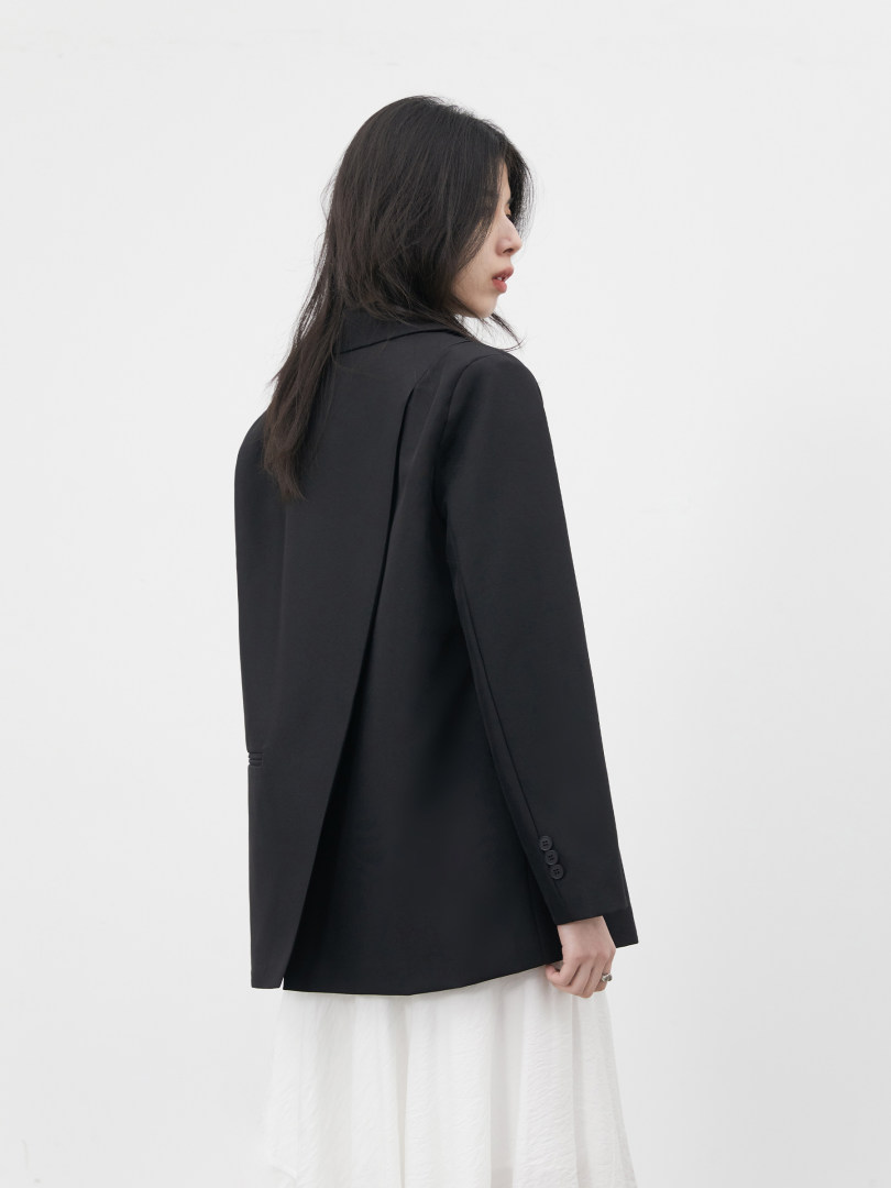 Black tailored blazer worn by a model over a white skirt