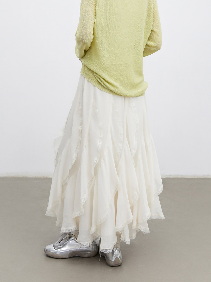 Model wearing a pale yellow knit top with a layered white skirt and silver shoes