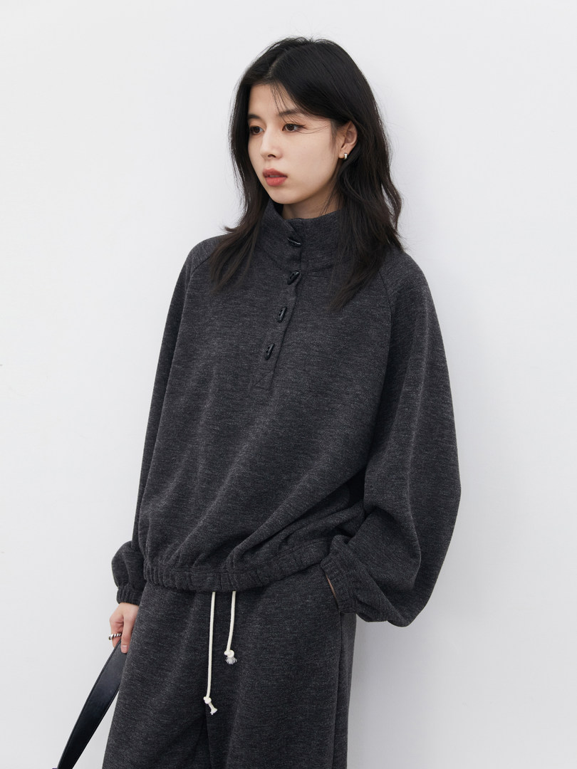 Model wearing a dark gray loungewear set with a high-neck pullover and drawstring pants