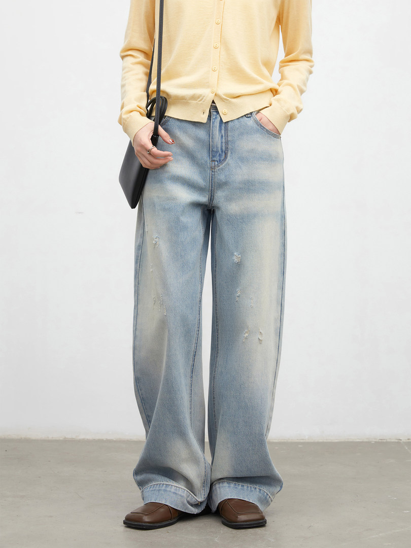Model wearing a pale yellow cardigan with light-wash wide-leg distressed jeans and brown shoes