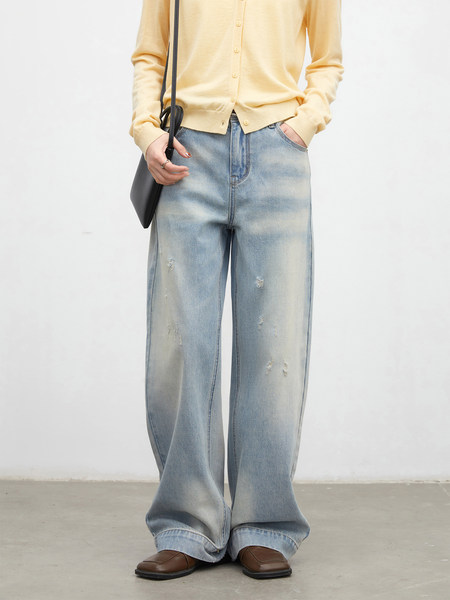 Model wearing a pale yellow cardigan with light-wash wide-leg distressed jeans and brown shoes