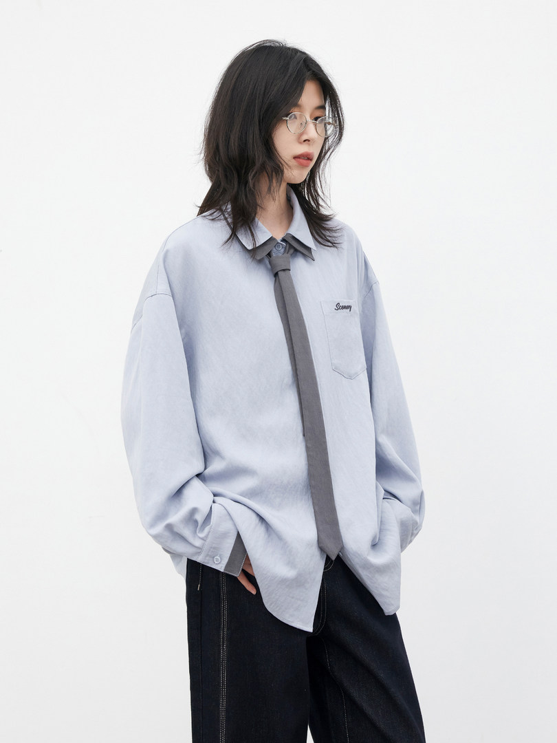 Model wearing a light blue oversized button-up shirt with a tie detail