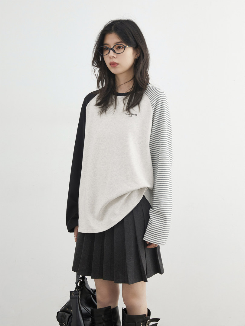 Model wearing a black-and-white long-sleeve top with a pleated black skirt and boots