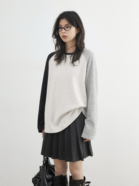Model wearing a black-and-white long-sleeve top with a pleated black skirt and boots