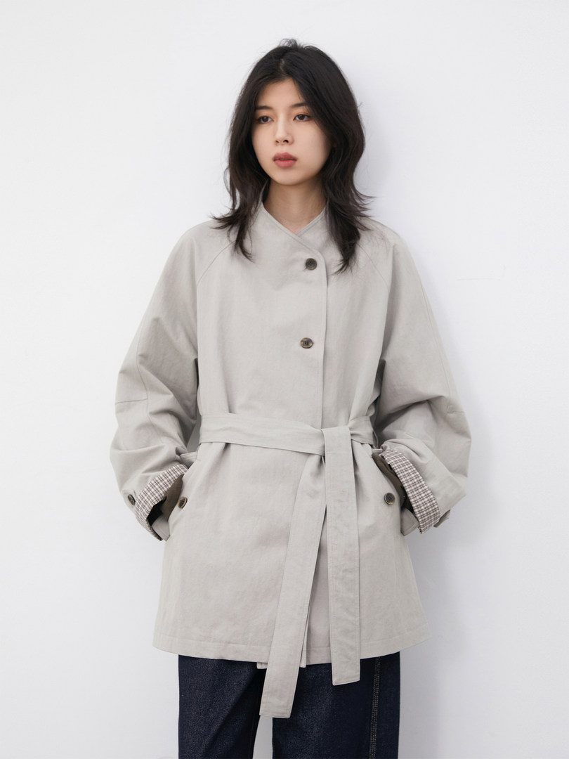 Model wearing a light beige belted coat with button front