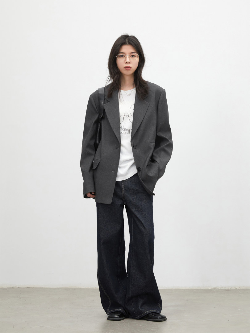 Model wearing a dark oversized blazer with a white graphic tee and wide-leg black jeans