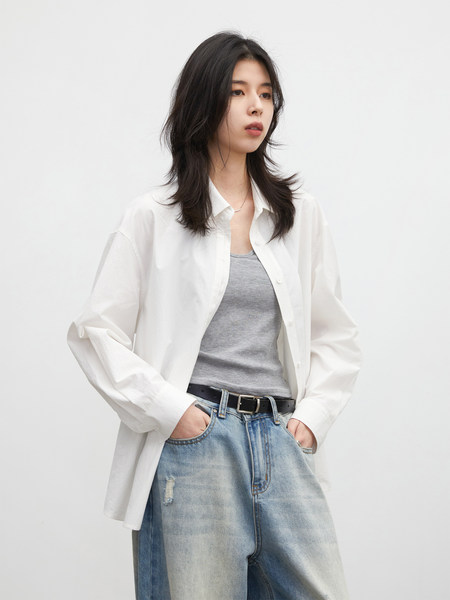Model wearing a white button-up shirt, gray tank top, and light-wash jeans