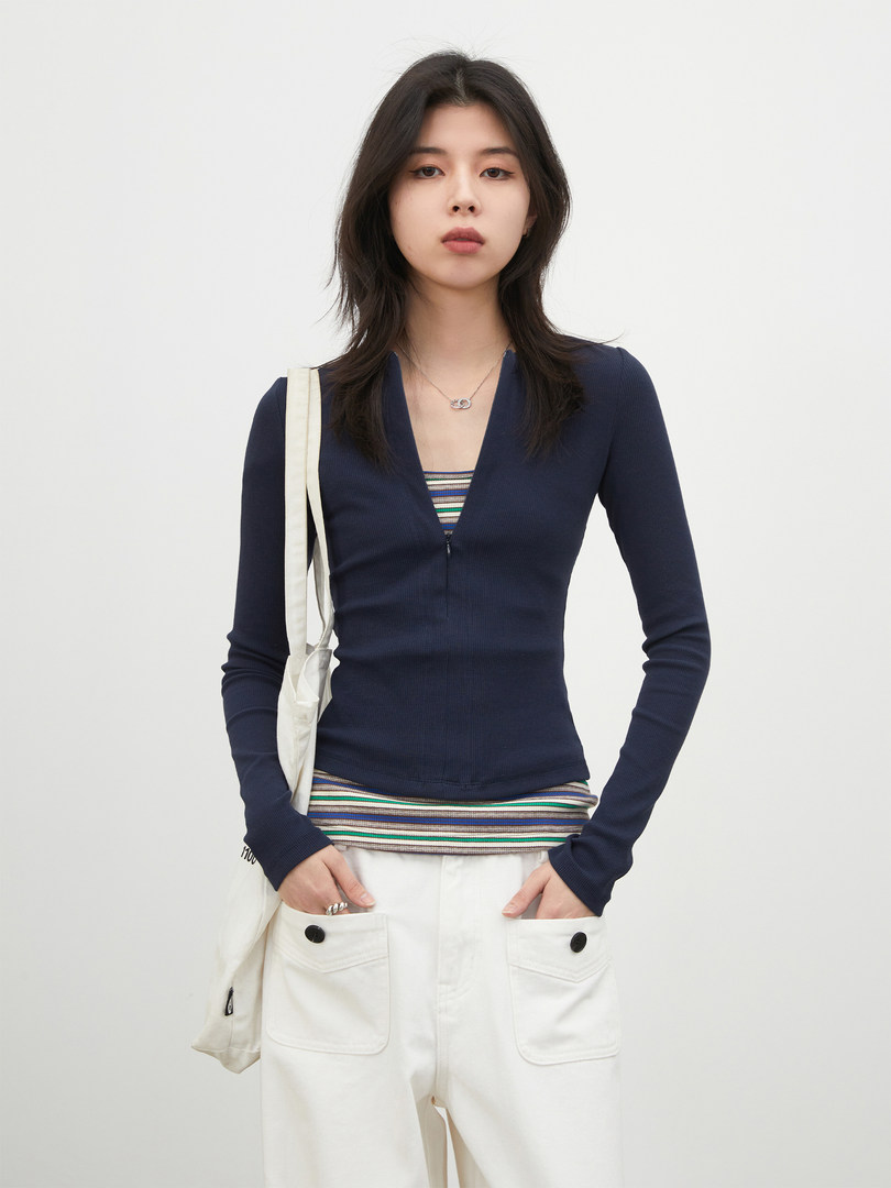 Model wearing a navy long-sleeve top with white pants and a tote bag