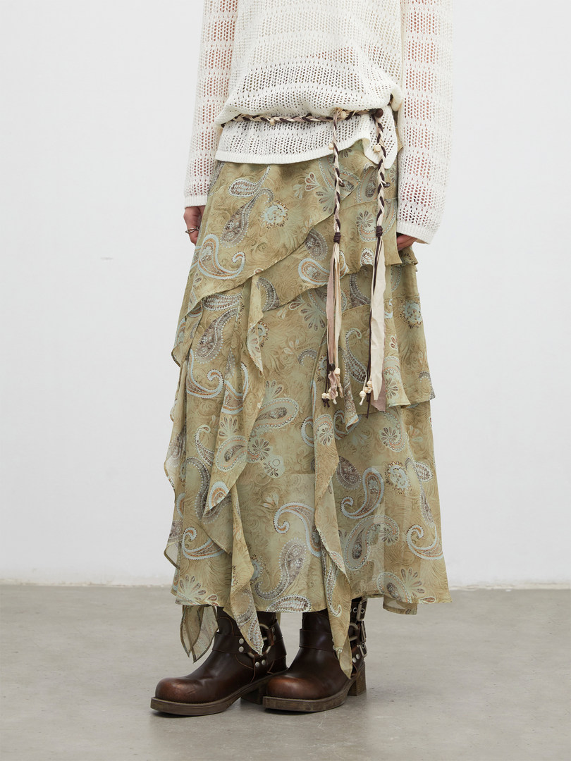 Model wearing a layered paisley skirt with a white knit top and brown boots