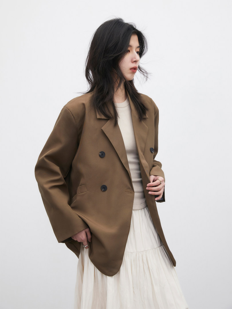 Brown double-breasted blazer worn by a model over a light outfit