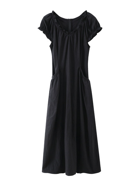 Black midi dress worn by a model seated on a sofa