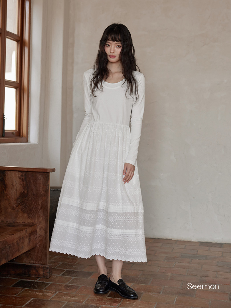 White long-sleeve dress with lace skirt worn by a model indoors