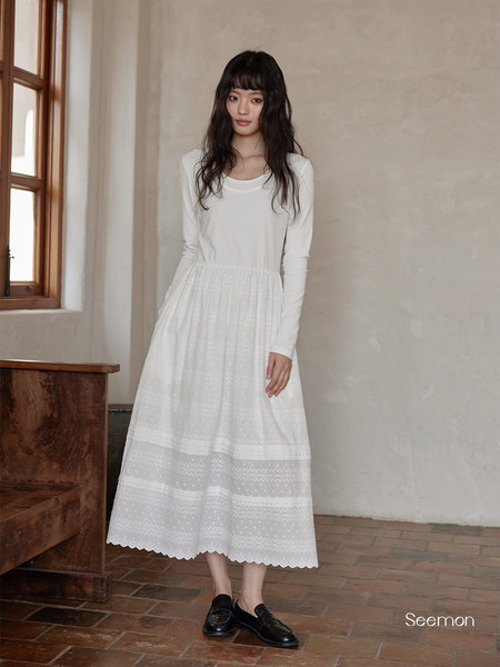 White long-sleeve dress with lace skirt worn by a model indoors