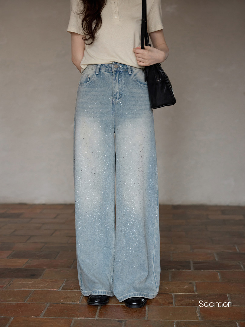 Light wash wide-leg jeans worn by a model with a black shoulder bag