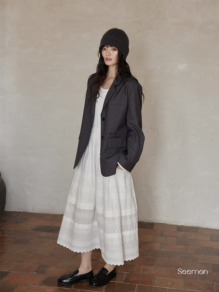 Model wearing a dark blazer, white lace midi skirt, and black loafers with a knit beanie