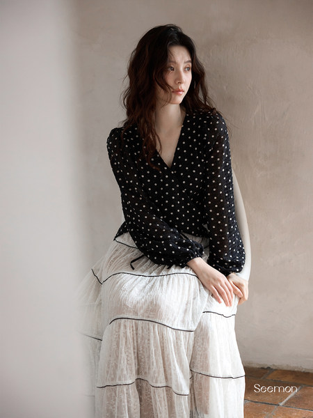 Model wearing a black polka dot blouse with a white sheer tiered skirt
