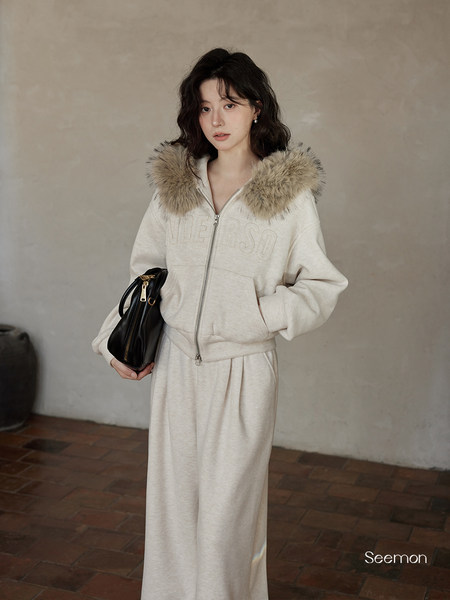 Model wearing a cream hooded zip-up set with fur-trimmed collar and matching wide-leg pants
