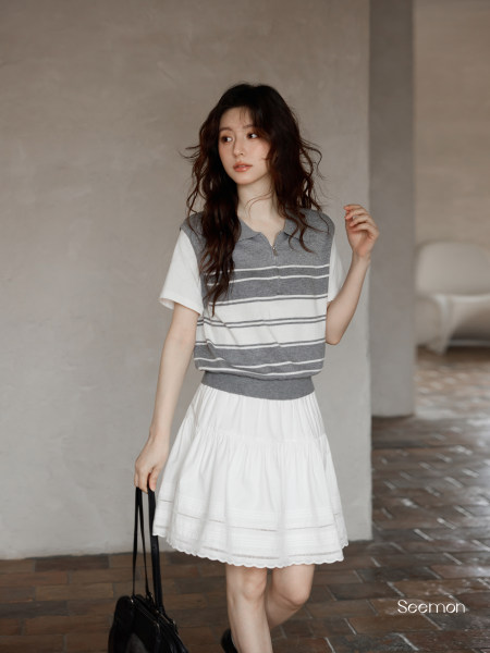 Model wearing a gray and white striped short-sleeve top with a white skirt