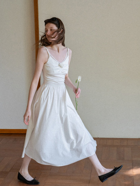 Woman wearing a white sleeveless midi dress with black flats