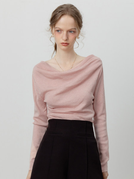 Model wearing a pink off-shoulder knit top with black high-waisted pants