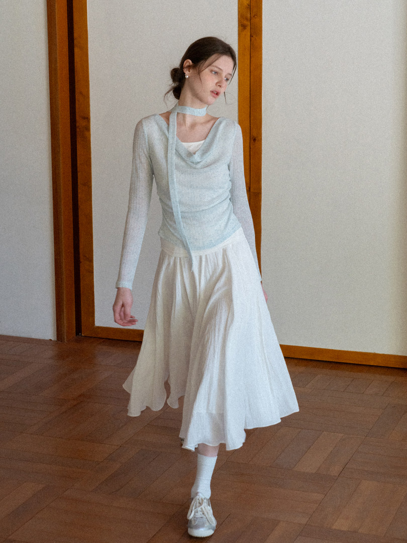 Model wearing a light blue sheer long-sleeve top with a white flowing skirt