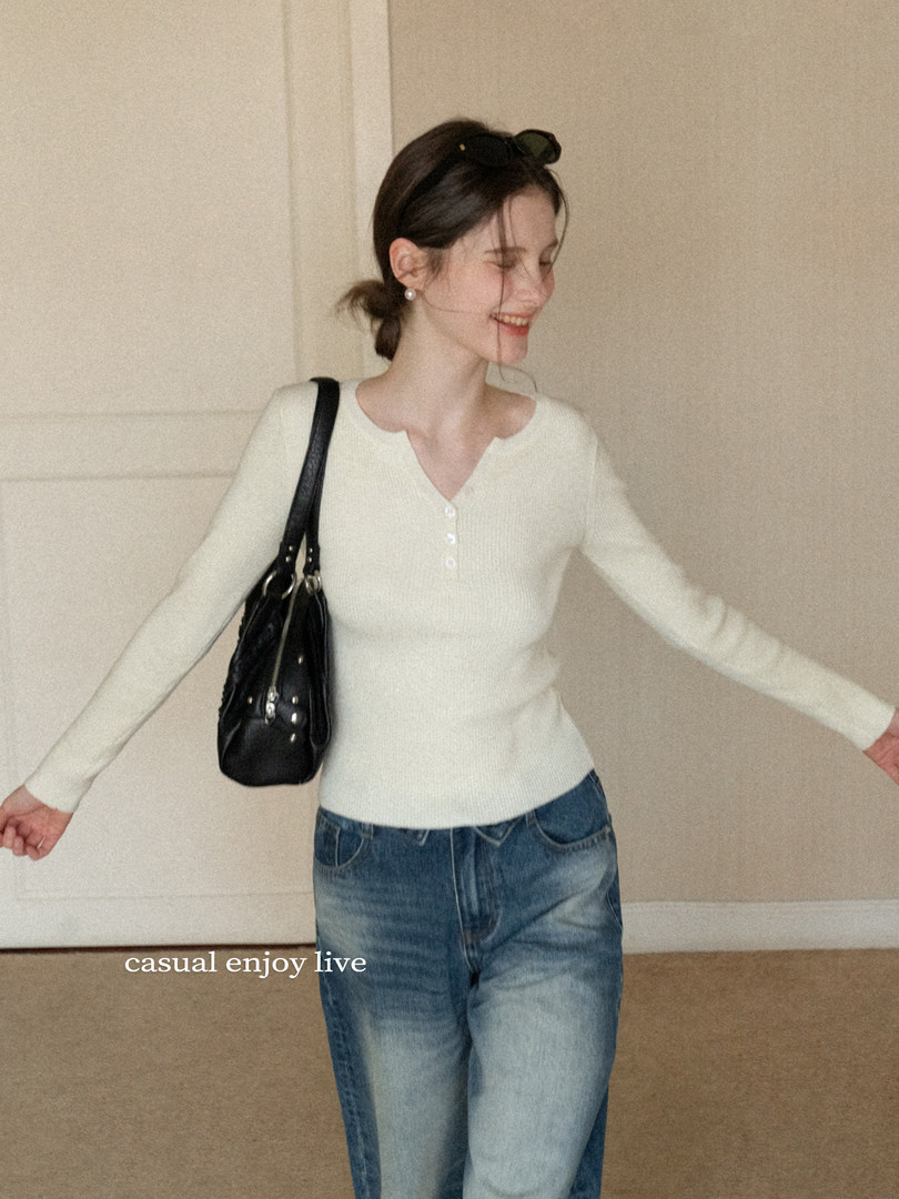 Woman wearing a white long-sleeve top with blue jeans and a black shoulder bag