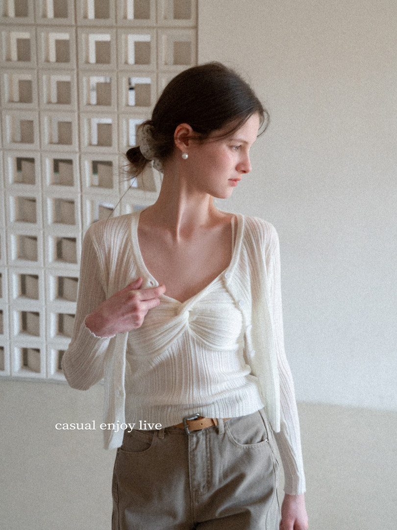 Model wearing a white ribbed long-sleeve cardigan top with brown trousers