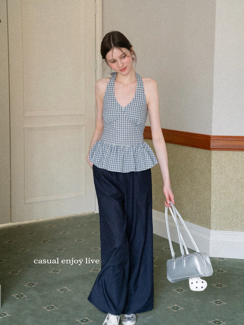 Model wearing a blue gingham halter top with wide-leg navy pants and a clear handbag