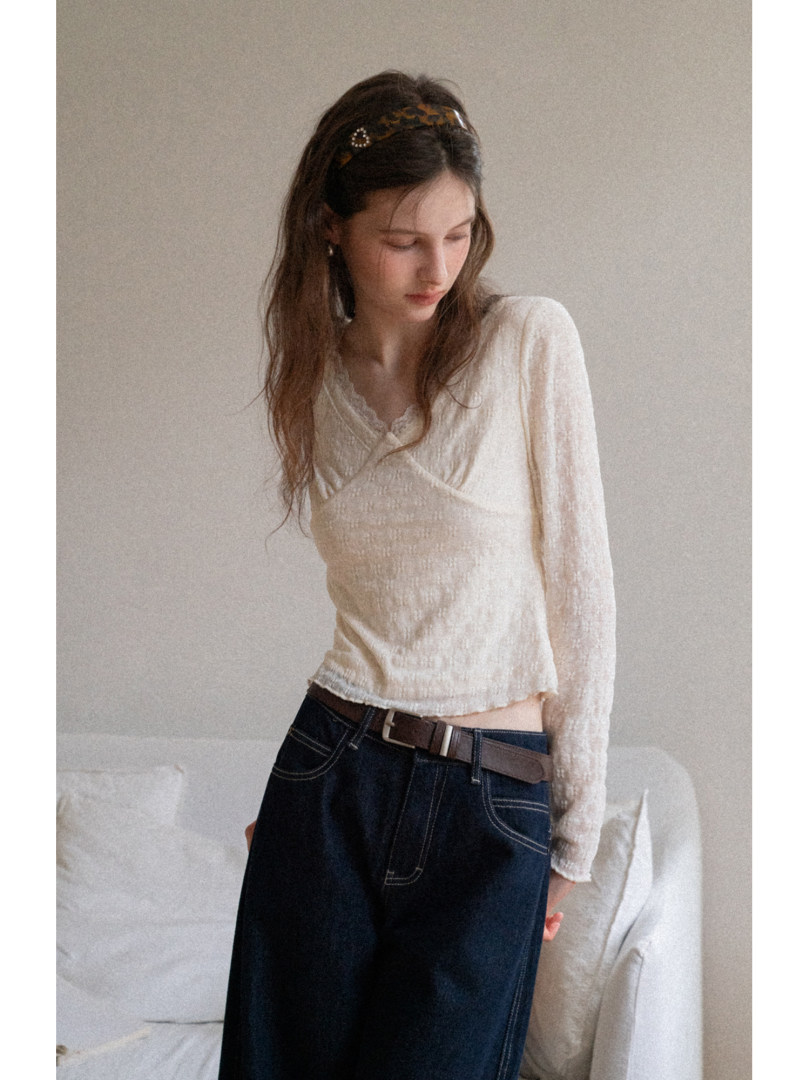 Woman wearing a cream long-sleeve wrap top with dark jeans