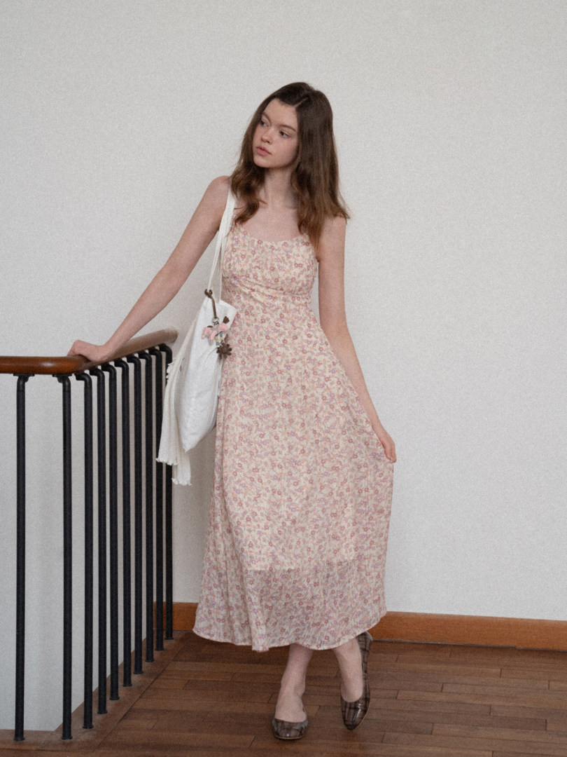 Model wearing a light pink floral sleeveless dress with a white shoulder bag