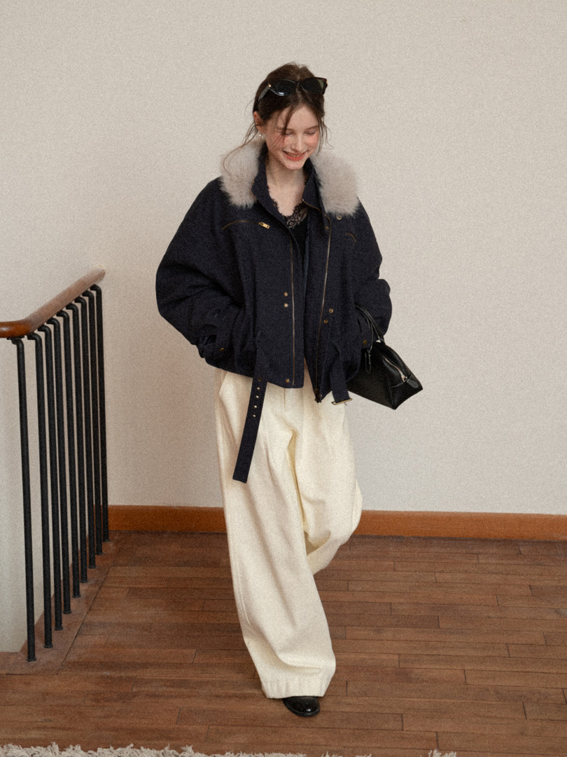 Woman wearing a navy jacket with fur collar and cream wide-leg pants