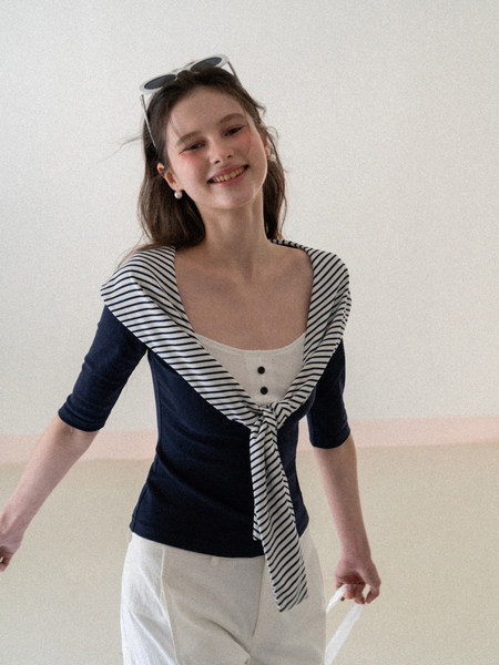 Woman wearing a navy and white striped sailor-style top with white pants
