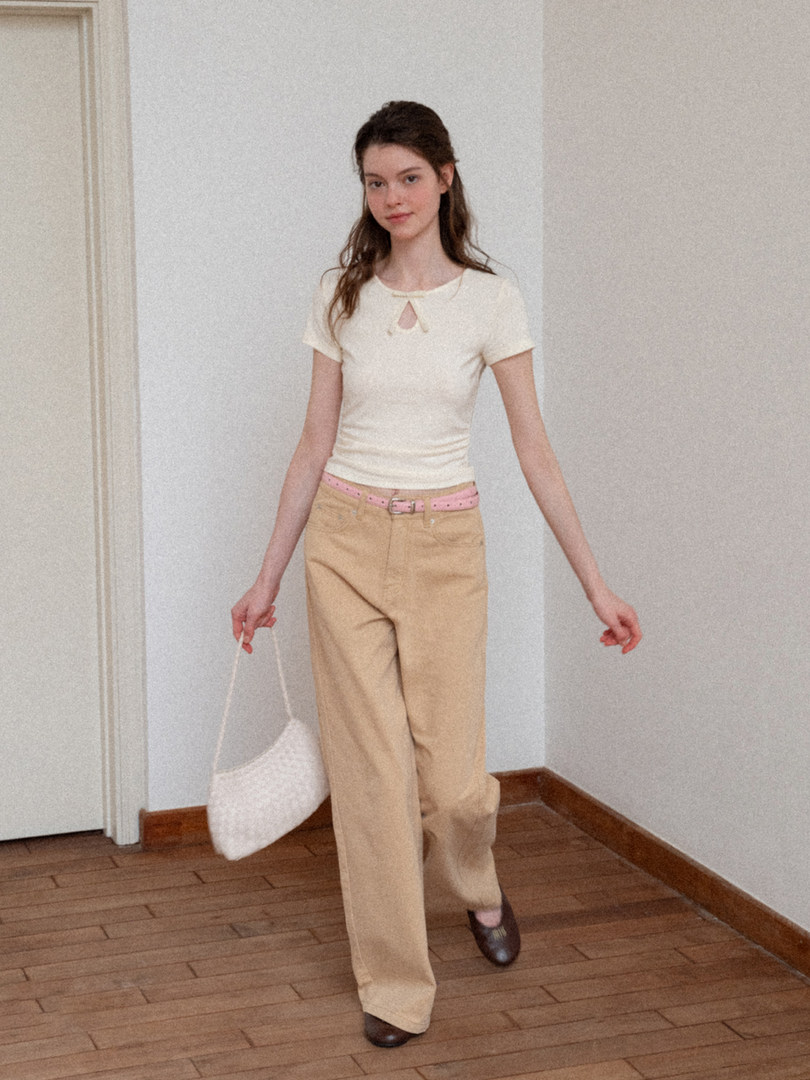 Model wearing a cream short-sleeve top and beige trousers with a pink belt