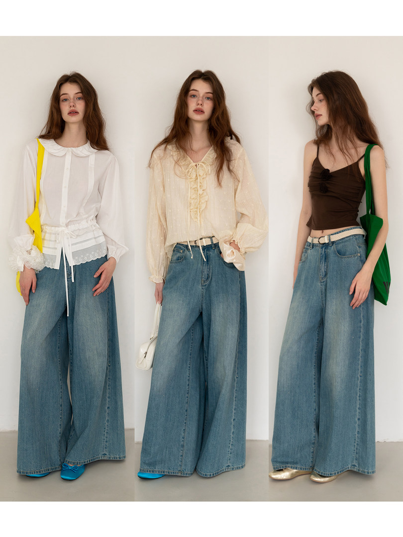 Three models wearing wide-leg blue jeans styled with different tops and handbags
