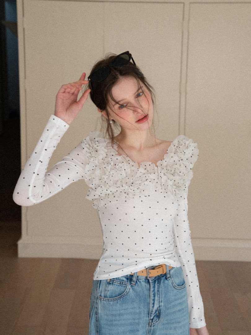 Woman wearing a white polka dot ruffled long-sleeve top with jeans