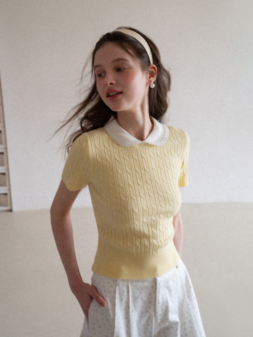 Model wearing a pale yellow short-sleeve knit top with a white Peter Pan collar