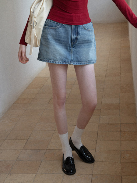 Model wearing a light blue denim mini skirt with a red top and black loafers