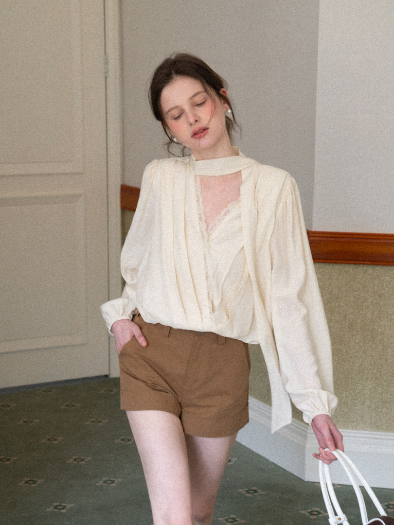 Model wearing a cream blouse with brown shorts