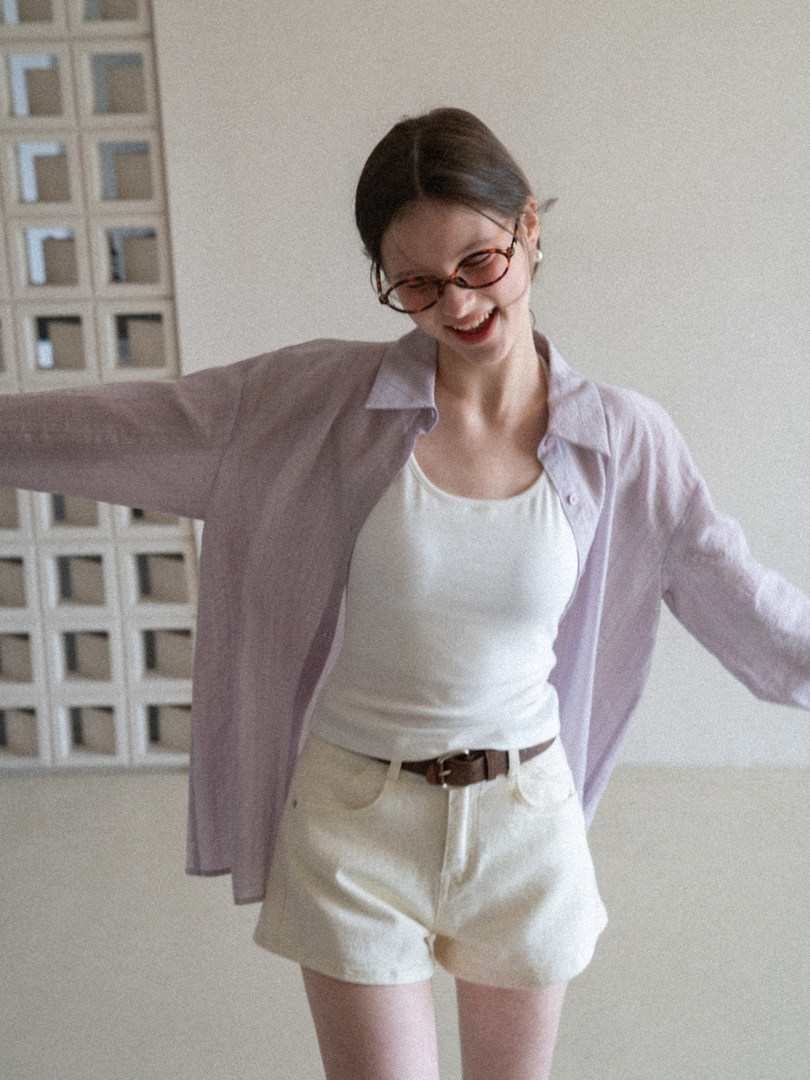 Model wearing a light lavender shirt with a white tank top and cream shorts